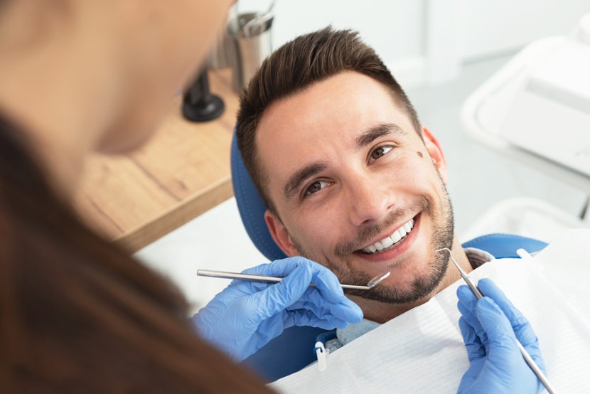 Man having a visit at the dentist's. Handsome patient sitting on chair at dentist office in dental clinic.