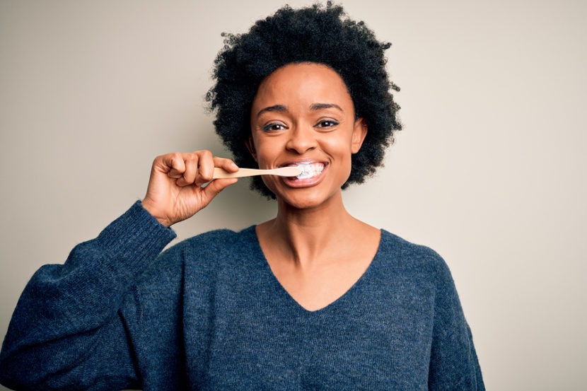African american woman brushing her teeth using tooth brush and oral paste, cleaning teeth and tongue as healthy health care morning routine