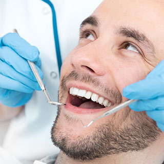 Young white man smiling while dentist doing dental checkup