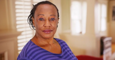 An elderly African American woman poses for a portrait in her house