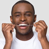 black man smiling with floss
