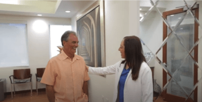 Senior adult smiling and female dentist smiling and putting her hand on his shoulder in friendly gesture