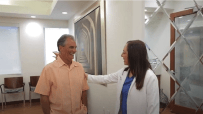 Senior adult smiling and female dentist smiling and putting her hand on his shoulder in friendly gesture