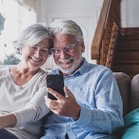 Smiling Sincere Mature Older Married Family Couple Holding Mobile Video Call Conversation With Friends